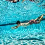 Dziecko pływające pod wodą w jasno oświetlonym basenie