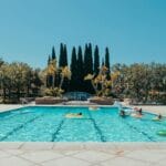 Osoby wypoczywające przy odkrytym, słonecznym basenie latem