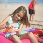 Dziewczynka na plaży w Portugalii nakłada krem z filtrem na słońcu