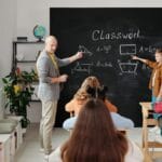 Nauczyciel tłumaczy zagadnienie na tablicy studentom w sali chemii