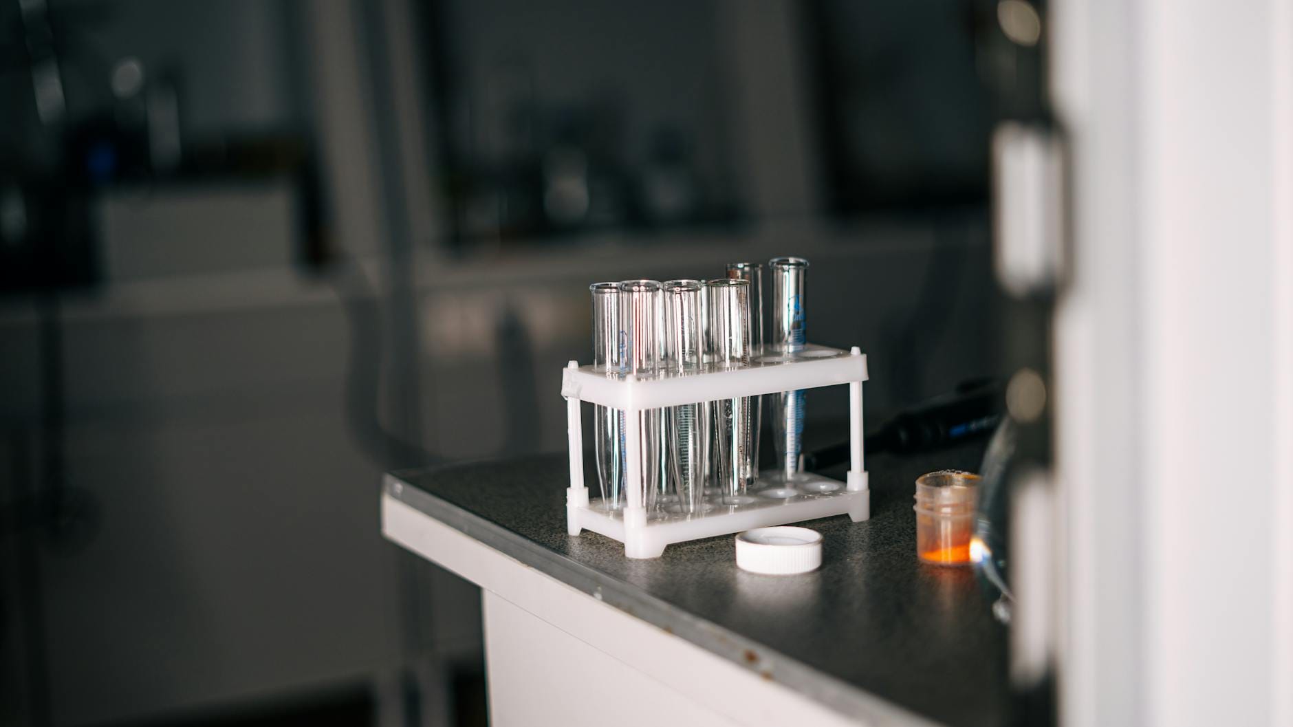 Probówki laboratoryjne i sprzęt na blacie w pracowni chemicznej