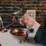 Ręce przygotowujące eliksir w kolbie w średniowiecznej pracowni chemicznej