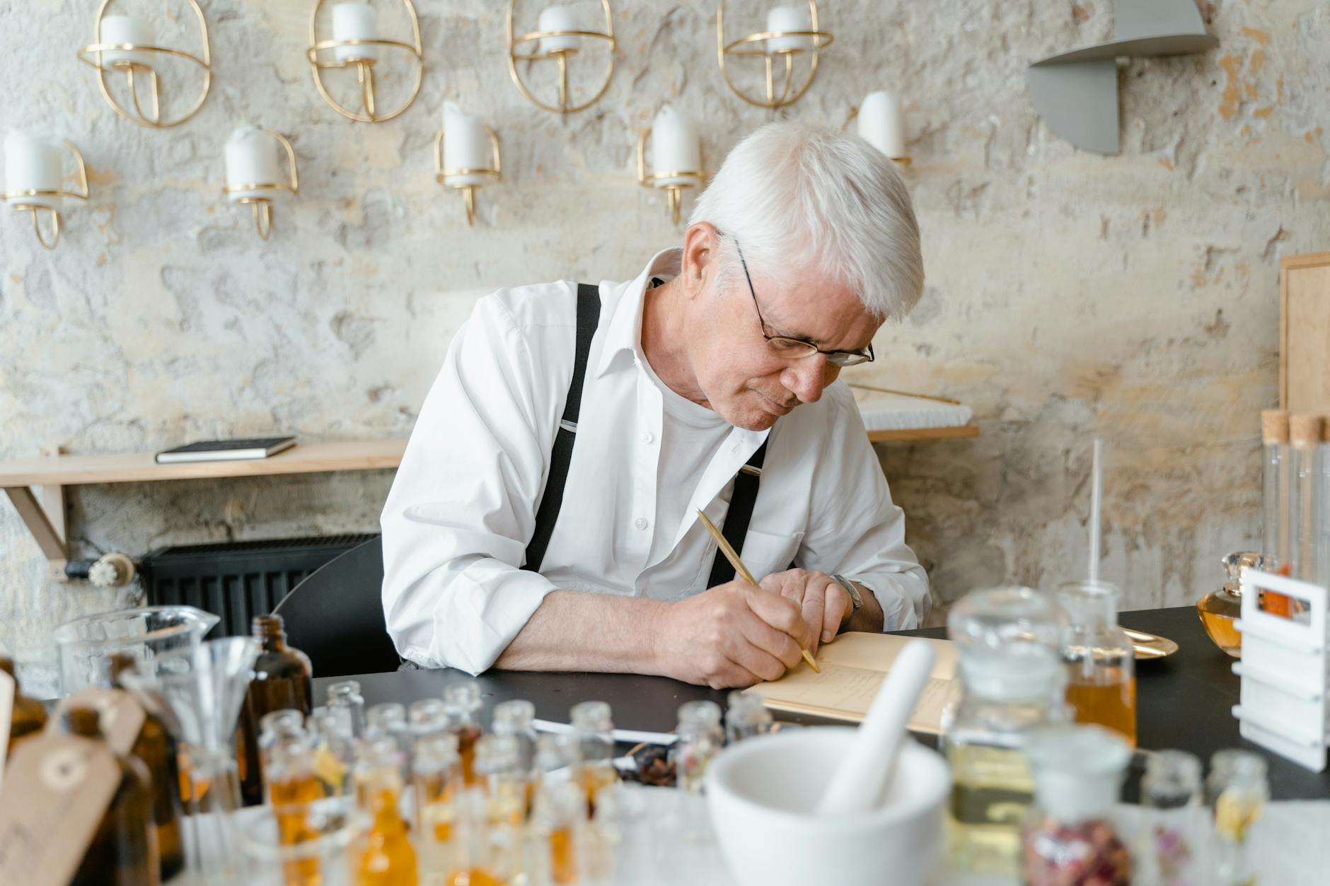 Starszy mężczyzna przy biurku analizuje szklane butelki z zapachami