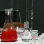 Szkło laboratoryjne z czerwonym i bezbarwnym roztworem w laboratorium