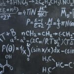 Tablica z zapisanymi kredą równaniami chemicznymi i matematycznymi