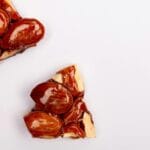 Zbliżenie na kruche migdały w karmelowej glazurze na białym tle