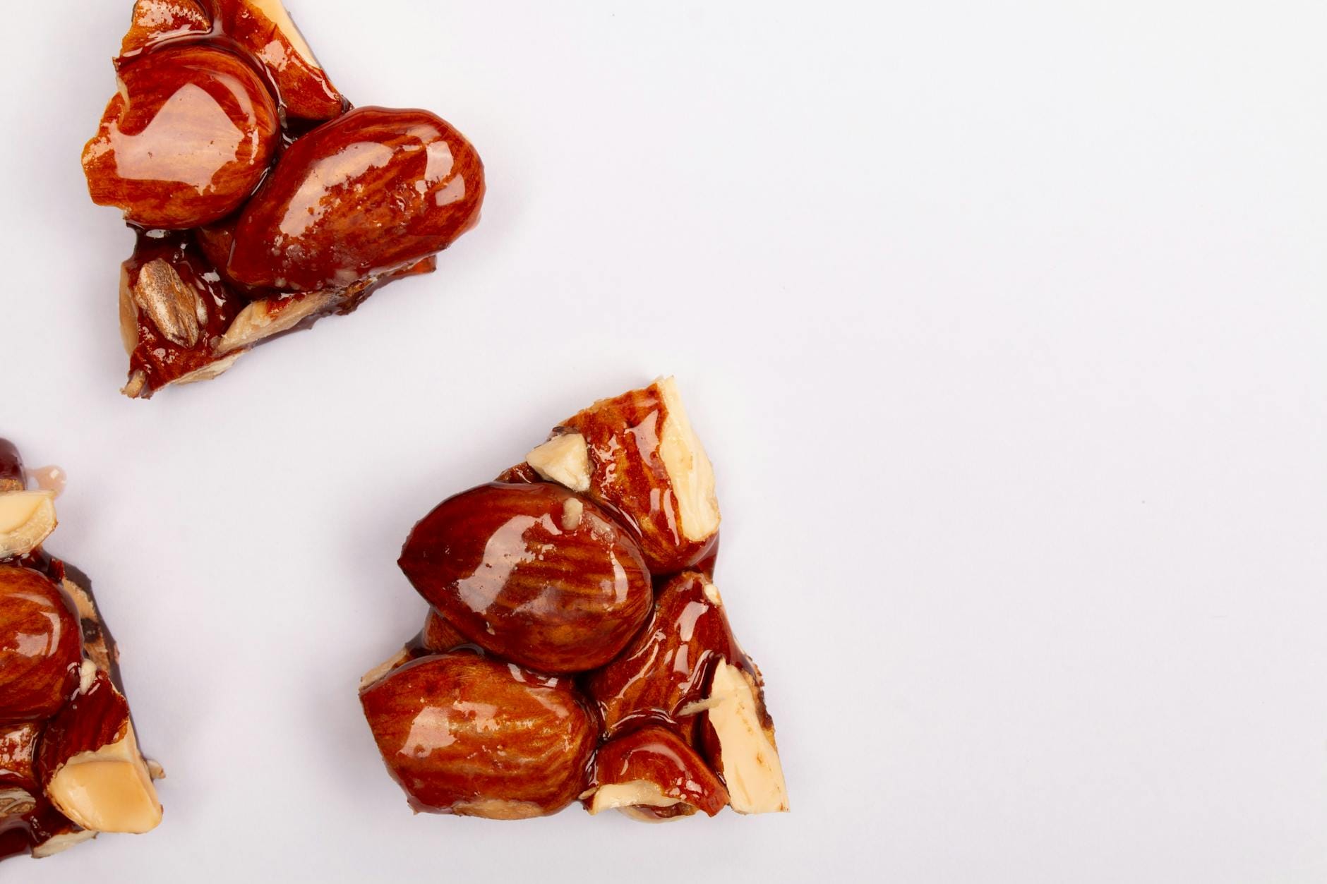 Zbliżenie na kruche migdały w karmelowej glazurze na białym tle