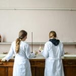 Równowaga kwasowo zasadowa: mocne i słabe kwasy oraz jak to zmienia pH roztworu Dwie chemiczki prowadzą doświadczenie w laboratorium nad roztworami kwasów