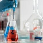 Chemik analizujący barwne roztwory w szkle laboratoryjnym