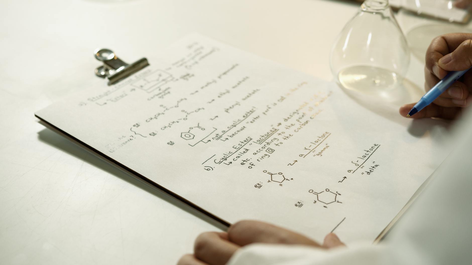 Zbliżenie notatek z wzorami chemicznymi na klipsie w laboratorium