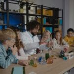 Nauczyciel chemii tłumaczy doświadczenie uczniom w szkolnej pracowni