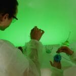 Naukowcy w laboratorium mieszają odczynniki w zielonym świetle