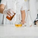 Dzieci w laboratorium wykonujące doświadczenie z kolorowymi roztworami